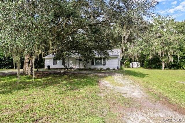 view of front facade with a storage shed and a front yard