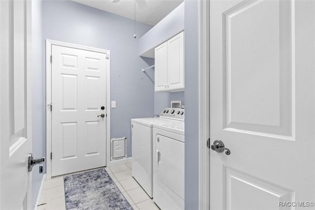 laundry room featuring cabinets, light tile patterned floors, a textured ceiling, and washer and dryer