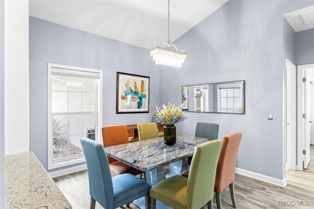 dining room with light hardwood / wood-style floors, lofted ceiling, and a notable chandelier