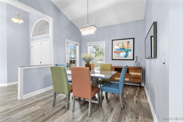 dining space with light hardwood / wood-style flooring, vaulted ceiling, and an inviting chandelier