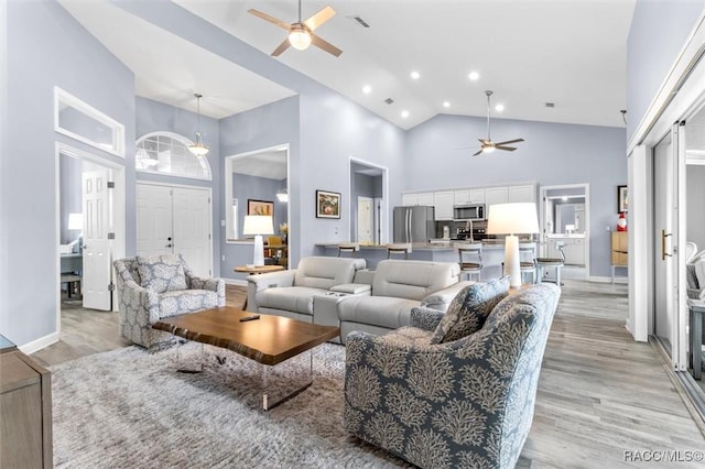 living room featuring ceiling fan, light hardwood / wood-style flooring, and a high ceiling