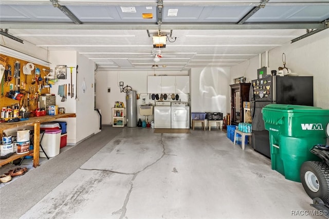 garage with a workshop area, washer and clothes dryer, a garage door opener, sink, and water heater