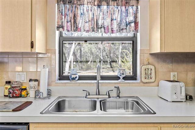 kitchen featuring stainless steel dishwasher, light brown cabinets, sink, and tasteful backsplash