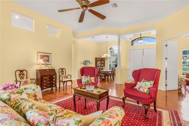 living room with ceiling fan with notable chandelier, ornamental molding, hardwood / wood-style floors, and ornate columns