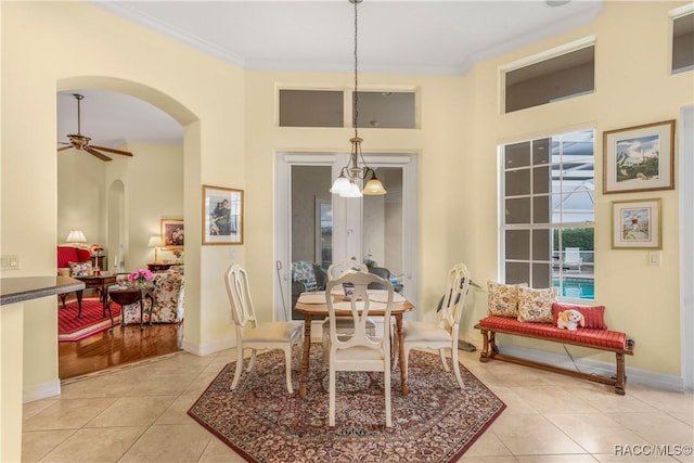 dining room featuring light tile patterned flooring, ornamental molding, and ceiling fan with notable chandelier