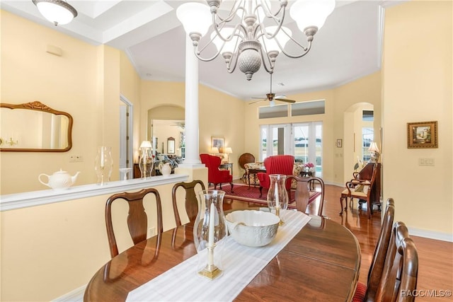 dining space with hardwood / wood-style floors, ceiling fan with notable chandelier, and ornate columns