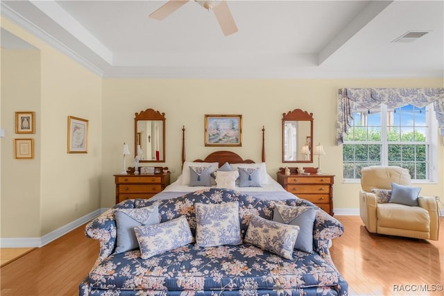 bedroom featuring hardwood / wood-style flooring, ornamental molding, and a tray ceiling