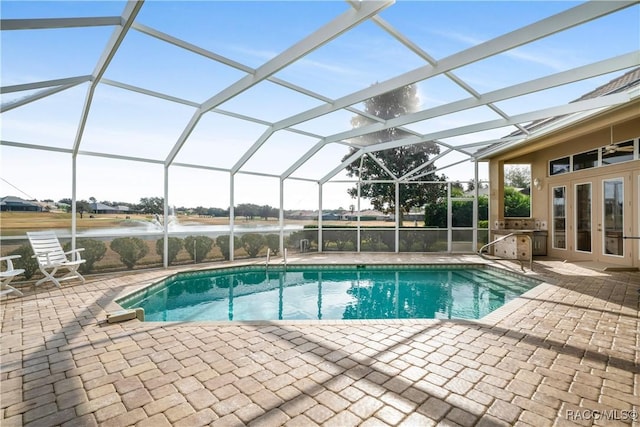 view of swimming pool featuring a patio, a water view, glass enclosure, and french doors