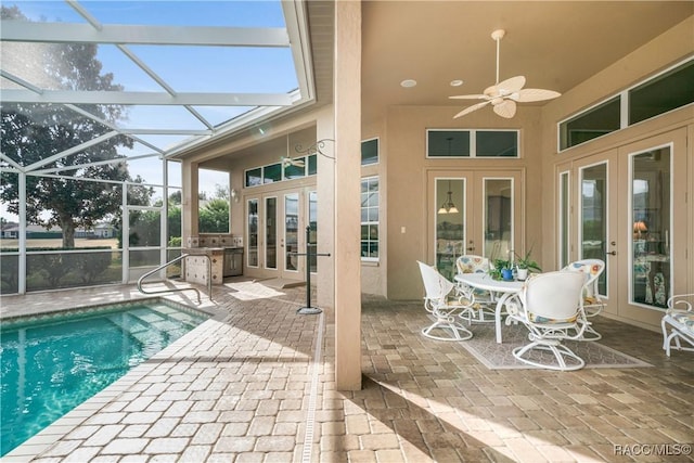 view of swimming pool featuring a patio, an outdoor kitchen, a lanai, ceiling fan, and french doors