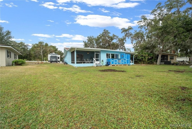 rear view of property featuring a sunroom and a lawn