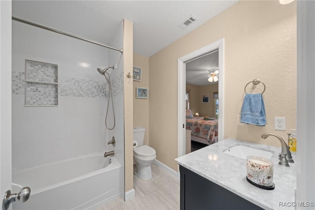 full bathroom with tiled shower / bath, ceiling fan, vanity, and toilet