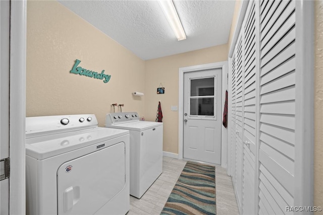 laundry area featuring light hardwood / wood-style floors, separate washer and dryer, and a textured ceiling