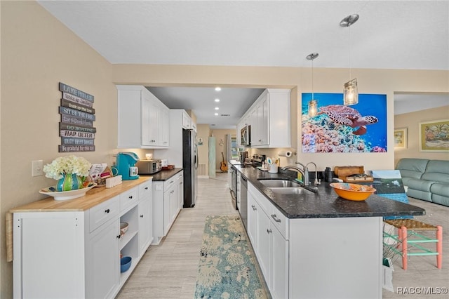 kitchen with sink, stainless steel appliances, a kitchen breakfast bar, pendant lighting, and white cabinets