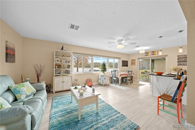 living room with ceiling fan and a textured ceiling