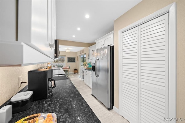 kitchen featuring stainless steel fridge, light hardwood / wood-style flooring, white cabinets, and dark stone counters