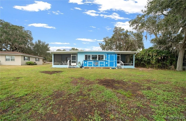 rear view of property featuring a sunroom and a lawn