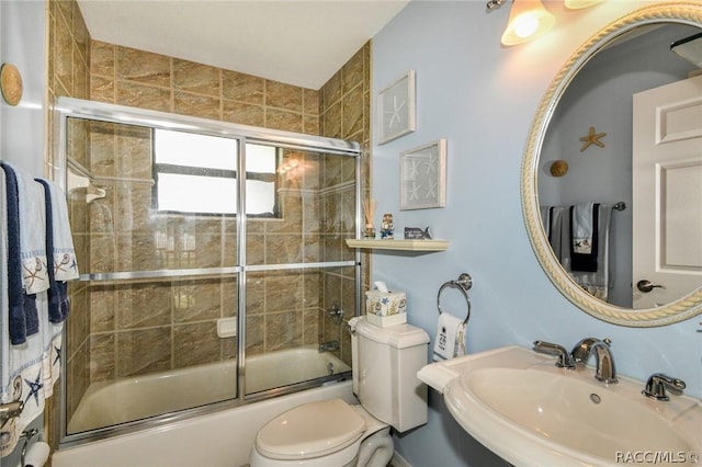 full bathroom featuring sink, shower / bath combination with glass door, and toilet