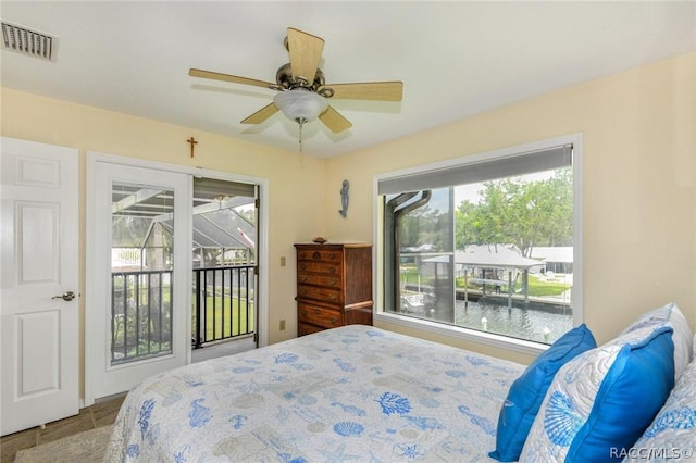 bedroom featuring access to outside, ceiling fan, and a water view