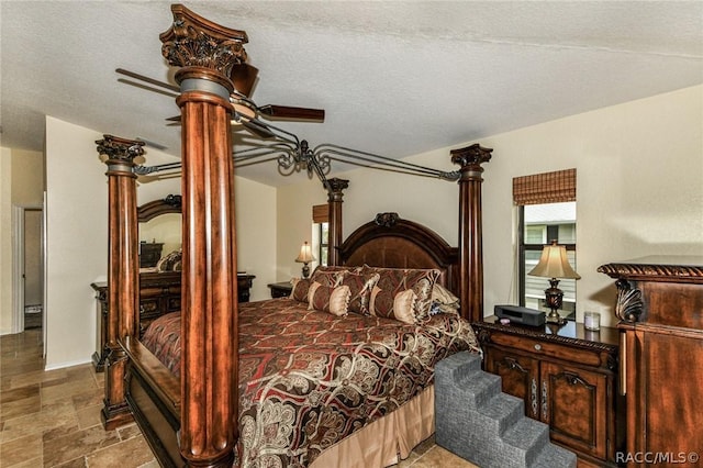 bedroom with ceiling fan, a textured ceiling, and ornate columns