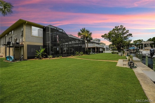 yard at dusk featuring glass enclosure and a dock