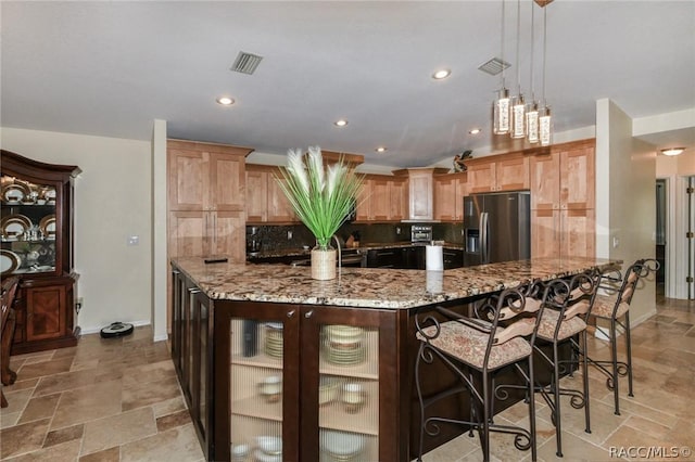 kitchen with stainless steel fridge with ice dispenser, tasteful backsplash, a kitchen breakfast bar, light stone countertops, and pendant lighting