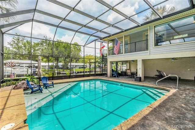 view of swimming pool featuring ceiling fan, a patio, and glass enclosure