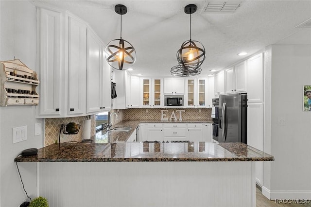 kitchen featuring built in microwave, stainless steel fridge with ice dispenser, backsplash, kitchen peninsula, and decorative light fixtures