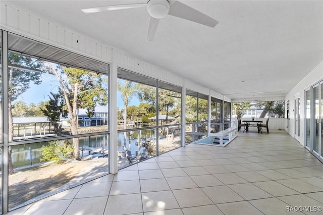 unfurnished sunroom with a water view and ceiling fan