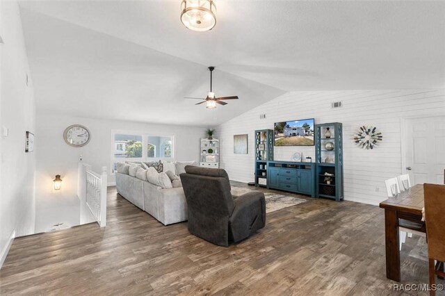 living room with lofted ceiling, ceiling fan, dark wood-type flooring, and wood walls