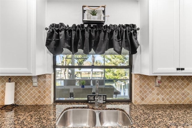 details with decorative backsplash, white cabinetry, sink, and dark stone counters