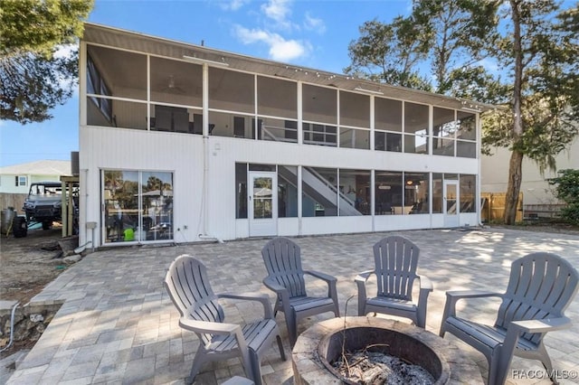 back of property featuring a patio, an outdoor fire pit, and a sunroom