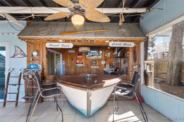 bar with ceiling fan, light tile patterned flooring, and wooden walls