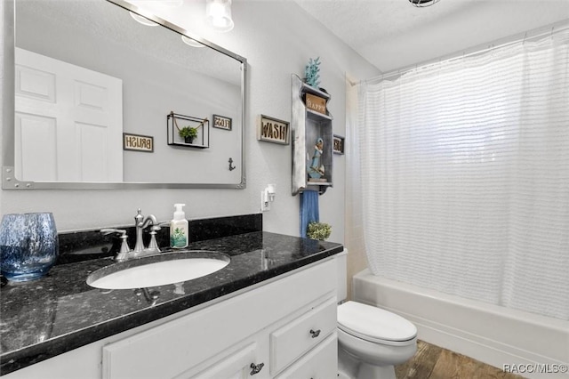 full bathroom with hardwood / wood-style floors, vanity, shower / bath combination with curtain, toilet, and a textured ceiling