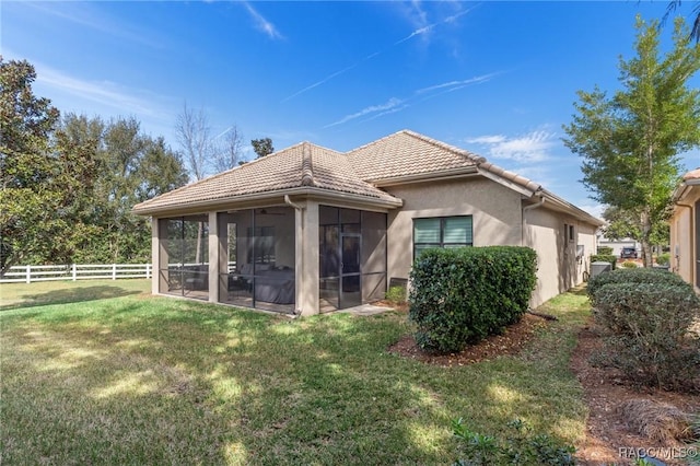 rear view of property featuring a yard and a sunroom