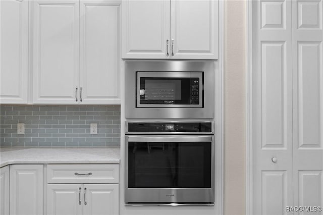 kitchen with backsplash, stainless steel appliances, white cabinets, and light stone countertops