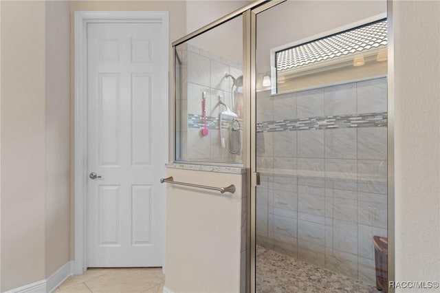 bathroom with a shower with door and tile patterned floors