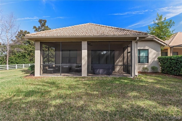 rear view of property featuring a sunroom and a lawn