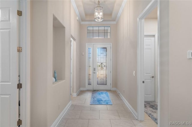 tiled foyer featuring an inviting chandelier and ornamental molding