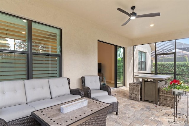 view of patio with ceiling fan, an outdoor living space, and glass enclosure