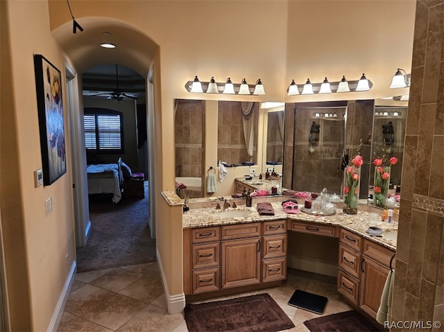 bathroom with a tile shower, ceiling fan, tile patterned flooring, and vanity