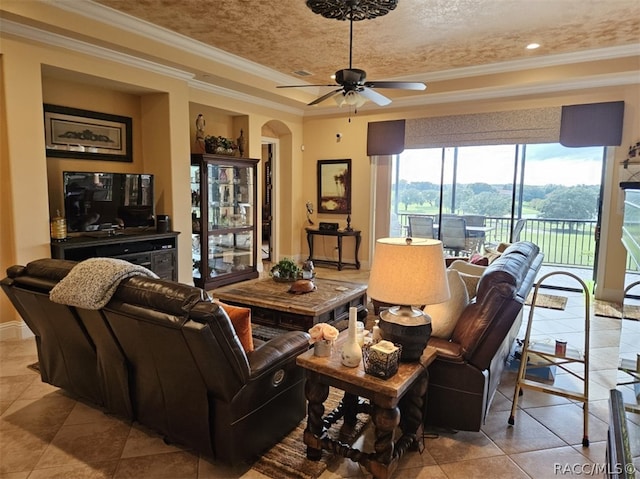 living room with ornamental molding, a textured ceiling, a tray ceiling, ceiling fan, and light tile patterned flooring