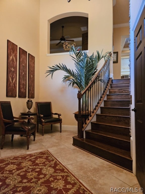 stairs with ceiling fan and ornamental molding