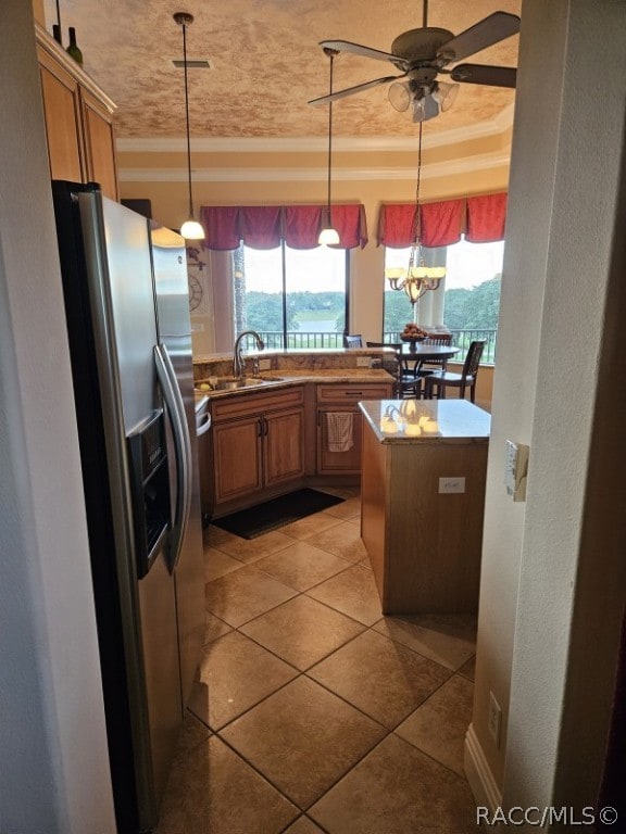 kitchen with stainless steel fridge, sink, a kitchen island, and decorative light fixtures