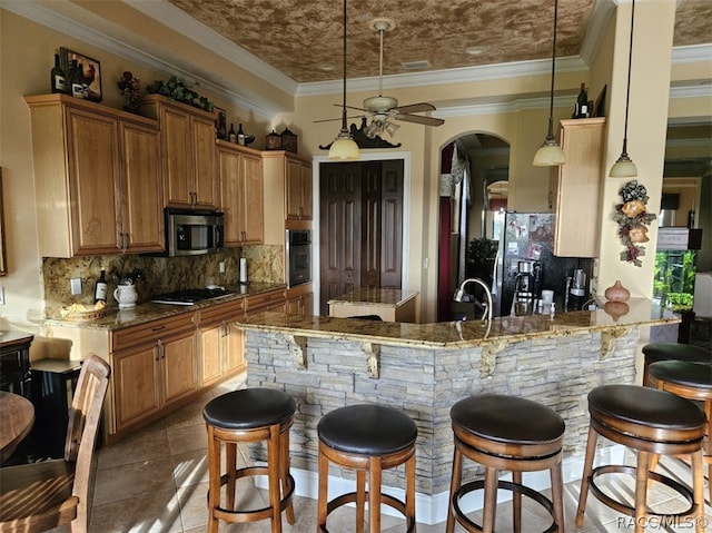 kitchen with stainless steel appliances, a kitchen breakfast bar, kitchen peninsula, dark stone countertops, and decorative light fixtures