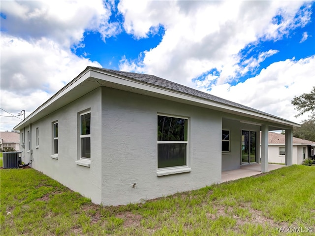 view of side of home with cooling unit, a patio area, and a yard