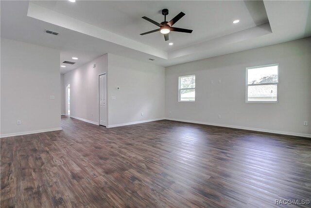 unfurnished room featuring ceiling fan, dark wood-type flooring, and a tray ceiling