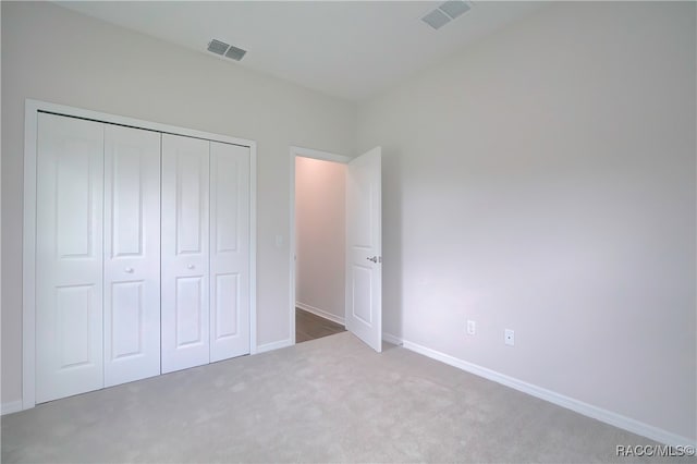 unfurnished bedroom with light colored carpet and a closet