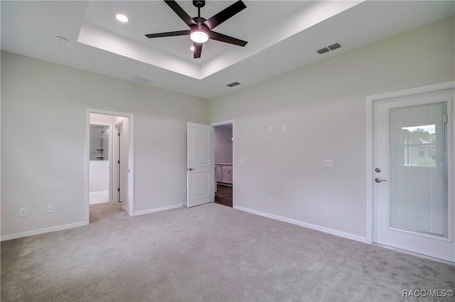 unfurnished bedroom with a raised ceiling, ceiling fan, and light colored carpet