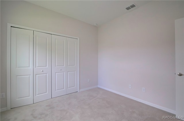 unfurnished bedroom with light carpet and a closet