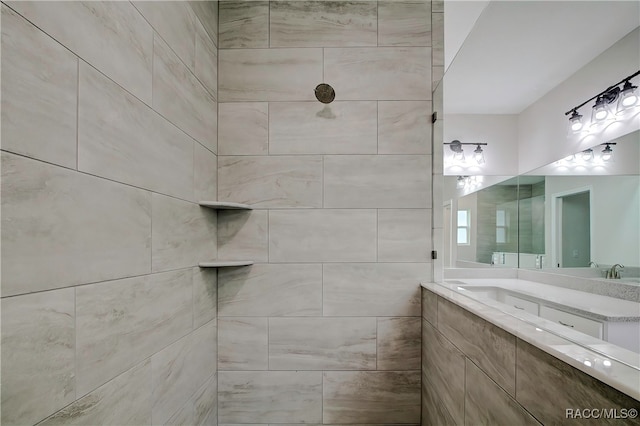 bathroom with a tile shower and vanity